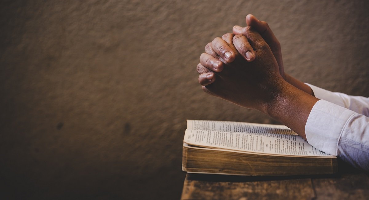 Hands folded in prayer on a Holy Bible